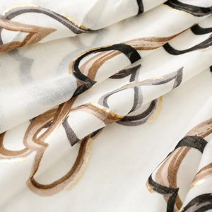 Close-up of lightweight white scarf featuring golden foil heart pattern and soft texture