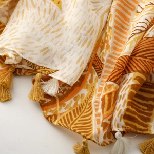 Detailed close-up of palm tree print fabric with decorative yellow fringe tassels