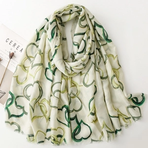 Detail of cotton linen scarf with green heart patterns and delicate fringed edges