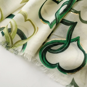 Detail of cream cotton-linen scarf featuring green hearts and gold foil metallic printing