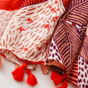 Detail of tropical palm leaf print scarf with red and pink handmade fringe tassels