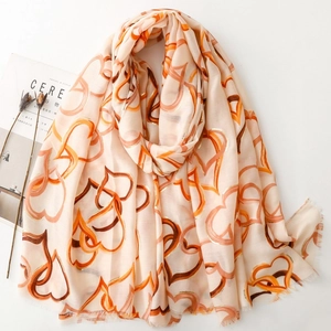 Linen feel scarf with orange heart patterns and soft frayed edges on white backdrop