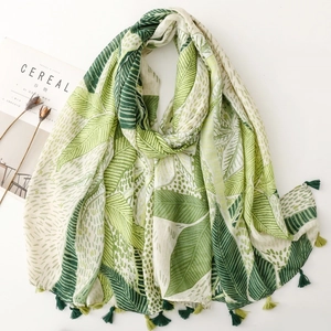 Detail of tropical green leaf print scarf with alternating two-tone decorative tassels