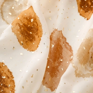 Vue macro d'une écharpe aux motifs lavis d'encre et textures de feuilles dorées