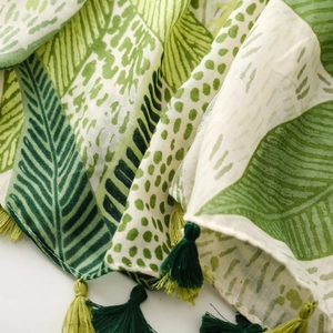 Close-up of tropical leaf print scarf featuring green dual-tone fringe tassels