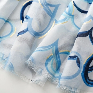 Detail of light blue linen-feel scarf with gold heart prints and fringe edges
