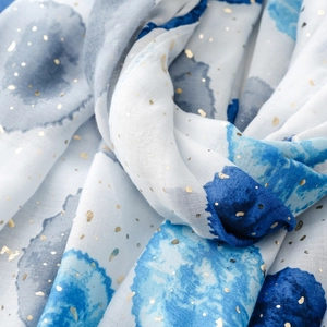 Gros plan détaillé de l'écharpe en soie blanche avec motifs aquarelle bleus et dorures