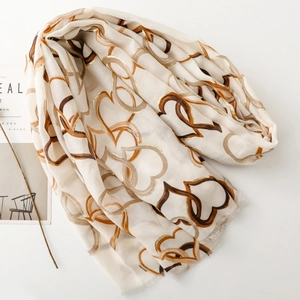 Detail of white cotton linen scarf featuring metallic gold heart print and frayed edges