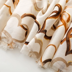 Detail of soft scarf with gold foil heart prints and textured frayed tassel edges