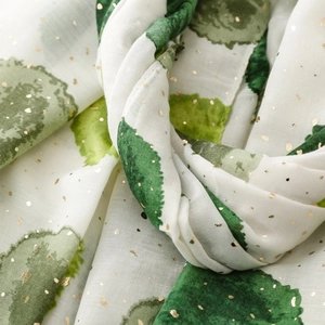 Gros plan d'une écharpe en soie blanche avec motifs à l'encre verte et pois dorés