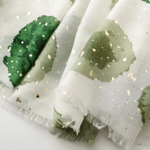 Détail d'une écharpe légère avec motifs aquarelle verts et pois dorés scintillants