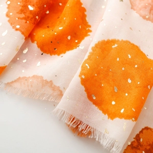 Détail d'une écharpe légère avec pois orange aquarelle et accents de feuilles d'or