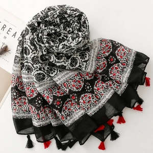 Détail de l'écharpe bohème à fleurs avec des glands noirs et rouges sur fond blanc