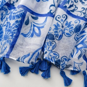Détail d'une écharpe fleurie bleue et blanche avec des franges douces et une texture en lin