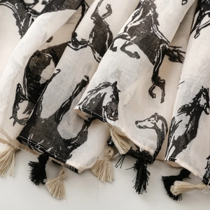 Détail de l'écharpe en coton et lin avec imprimé cheval noir et bordures à franges