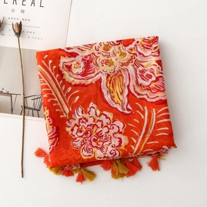 Flat lay detail of orange floral scarf with fringe and a magazine on white background