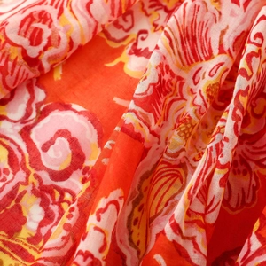 Close-up of red bohemian floral scarf fabric with intricate paisley patterns and tassels