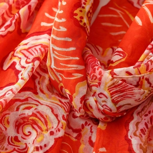 Macro shot of ethnic floral pattern on soft translucent orange and red scarf fabric