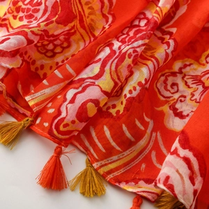 Close-up of ethnic floral print scarf featuring orange and gold fringe tassels