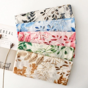 Detailed view of leaf pattern scarves with gold foil accents and fringe edges