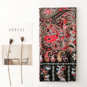 Detail of ethnic paisley floral scarf with fringe edges next to minimalist decor