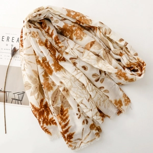 Detail of cotton linen scarf featuring golden leaf print and fringe on a magazine
