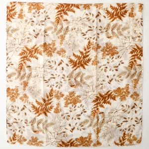 Detailed close-up of earth-toned botanical leaf prints on lightweight linen-feel scarf