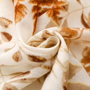 Detailed macro shot of cotton linen scarf featuring golden lush leaf prints on cream fabric