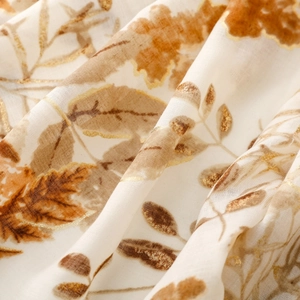 Macro detail of cotton-linen feel scarf showing golden foil leaf print and soft fabric texture