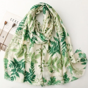 White linen-feel scarf with green leaf prints and gold foil outlines in natural drape