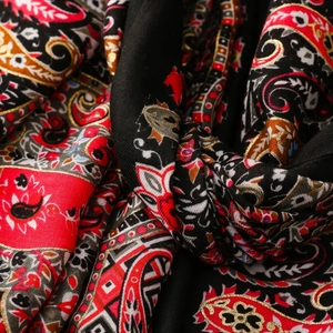 Close-up detail of paisley floral pattern on a vintage bohemian red and gold silk scarf