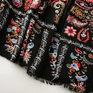 Close-up of bohemian paisley floral pattern and fine tassels on a soft black shawl