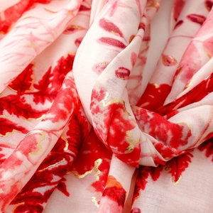 Detailed macro shot of red floral print with gold foil accents on linen feel scarf