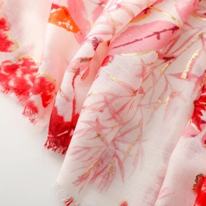 Detailed macro view of pink cotton linen scarf with gold foil floral print and fringe edges