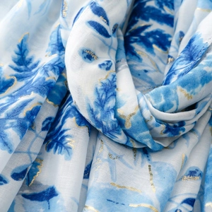 Detail of soft white linen-touch scarf featuring blue leaves and gold foil botanical patterns