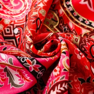 Detail of vintage ethnic scarf featuring golden paisley print and floral silk textures