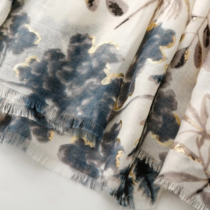 Detail of floral print scarf with gold foil accents and soft fringed edges on cotton linen