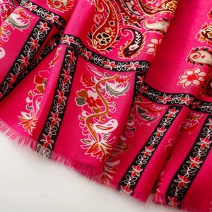 Close-up of rose red paisley scarf featuring floral patterns and delicate fringe edges