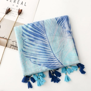 Detail of tropical leaf print scarf with gold thread embroidery and blue tassels