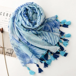 Close-up of blue tropical wave pattern scarf with metallic gold threads and fringe