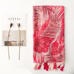 Close-up of tropical palm leaf print scarf with elegant red and pink fringed tassels