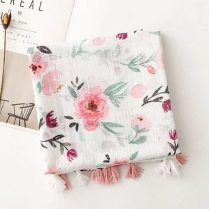 Detailed macro view of white floral scarf with pink flower prints and tassel fringe edge
