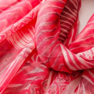 Detail of red floral scarf with gold metallic threads and soft fringed edges