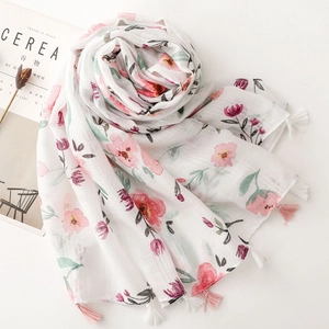 Detail of floral print scarf with pink tassels and cotton-linen texture on white base