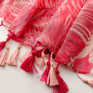 Detail of red and pink scarf fabric with gold silk threads and fringe tassels