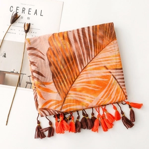Close-up of tropical palm leaf print scarf with orange and brown bicolor tassels