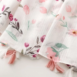 Close-up of pink tulip print and elegant tassel fringe on lightweight white scarf