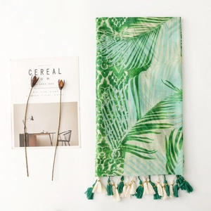 Detail of tropical palm leaf print scarf with tassels and breathable fabric texture
