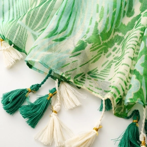 Detail of tropical leaf print scarf with gold lurex threads and green fringe tassels