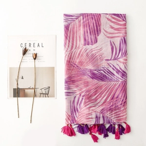 Macro shot of tropical palm leaf print scarf with pink and purple tassels on white background